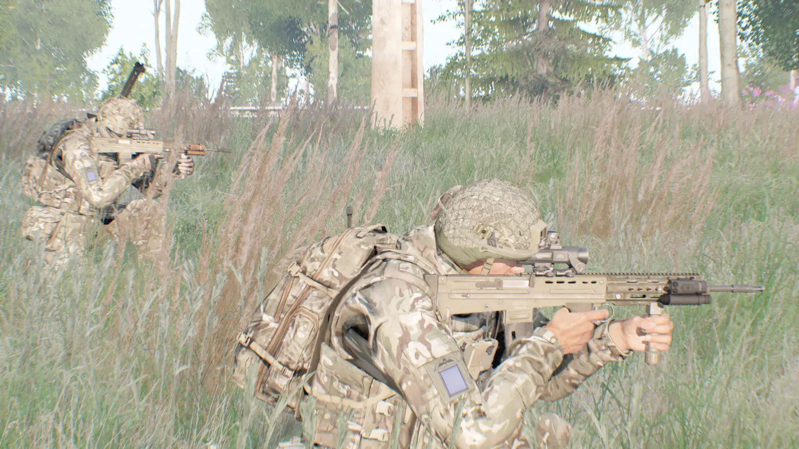 Riflemen in ghillie-netted helmets holding overwatch in tall grass